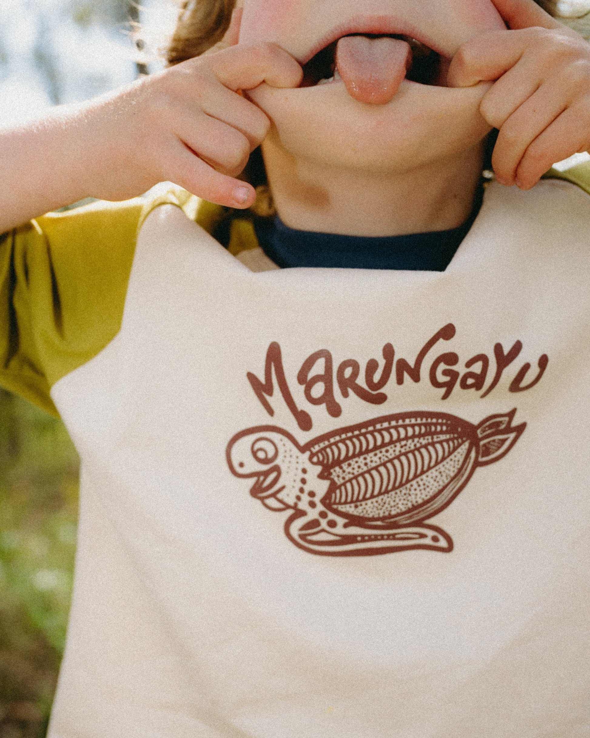 Child wearing a shirt with 'Marungayu' logo outdoors